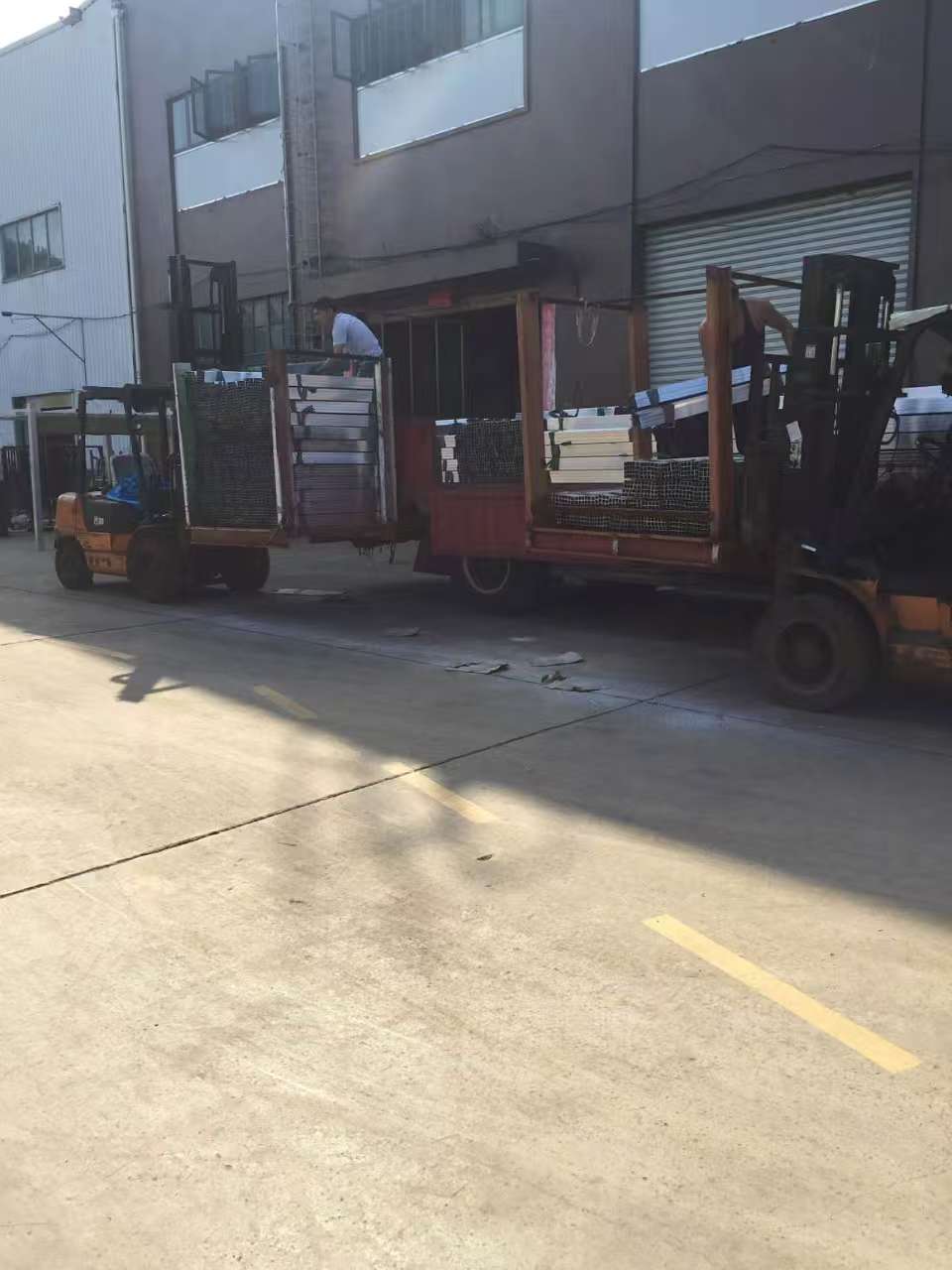 Worker using a forklift to load outdoor furniture in a warehouse for delivery.